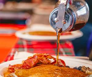 Pouring maple syrup over pancakes