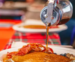Pouring maple syrup over pancakes
